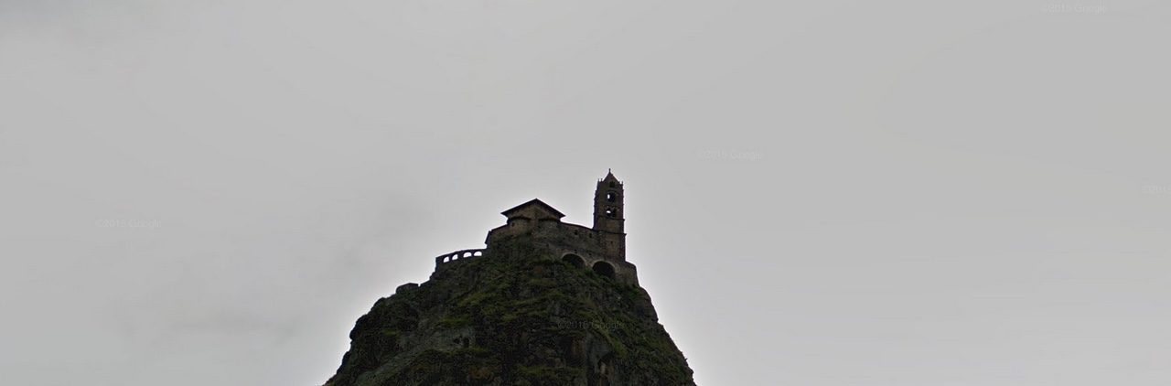 A stone church on a steep rocky hill beneath an overcast sky